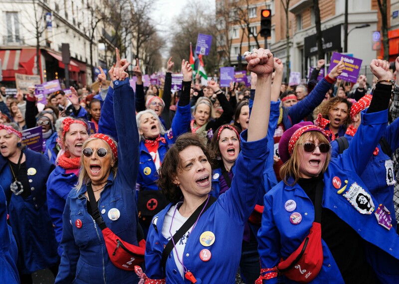A group of women dressed in blue shout jubilantly.