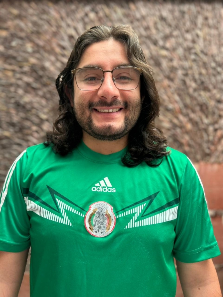 A man in a green football shirt smiles to camera
