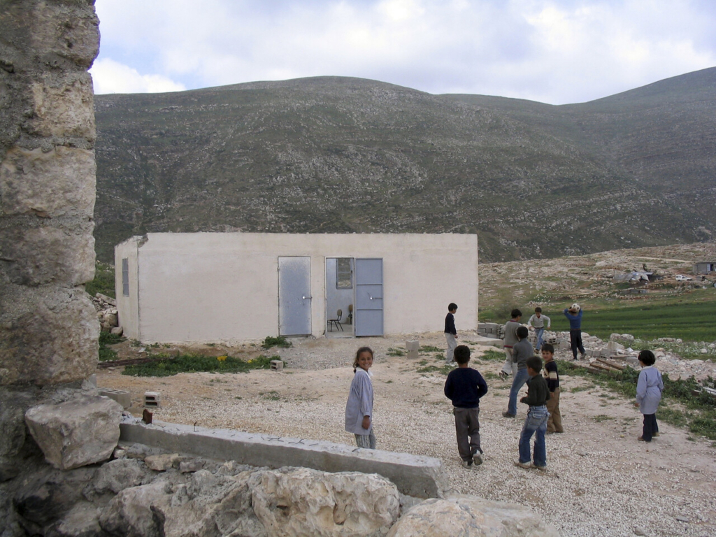 children in front of a building in a rural area