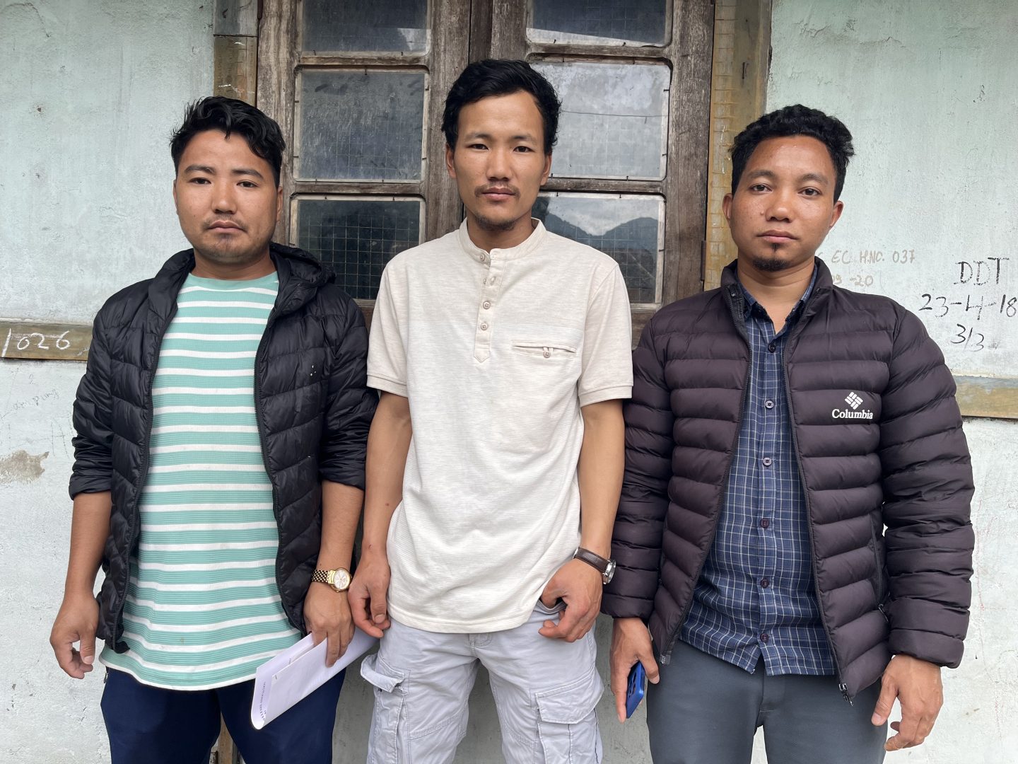 Three young men stand in front of a building in Phop village, Arunachal Pradesh, India