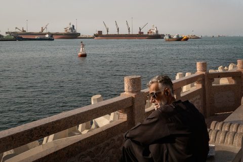A man observes oil tankers, general cargo ships, bulk carriers, and fishing boats anchored in the waters off Muscat near the Strait of Hormuz on June 18, 2026 in Muscat, Oman