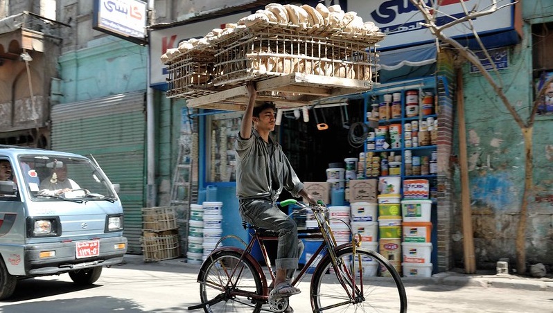 A man on a bicycle balances baskets of bread on his head in Cairo, Egypt